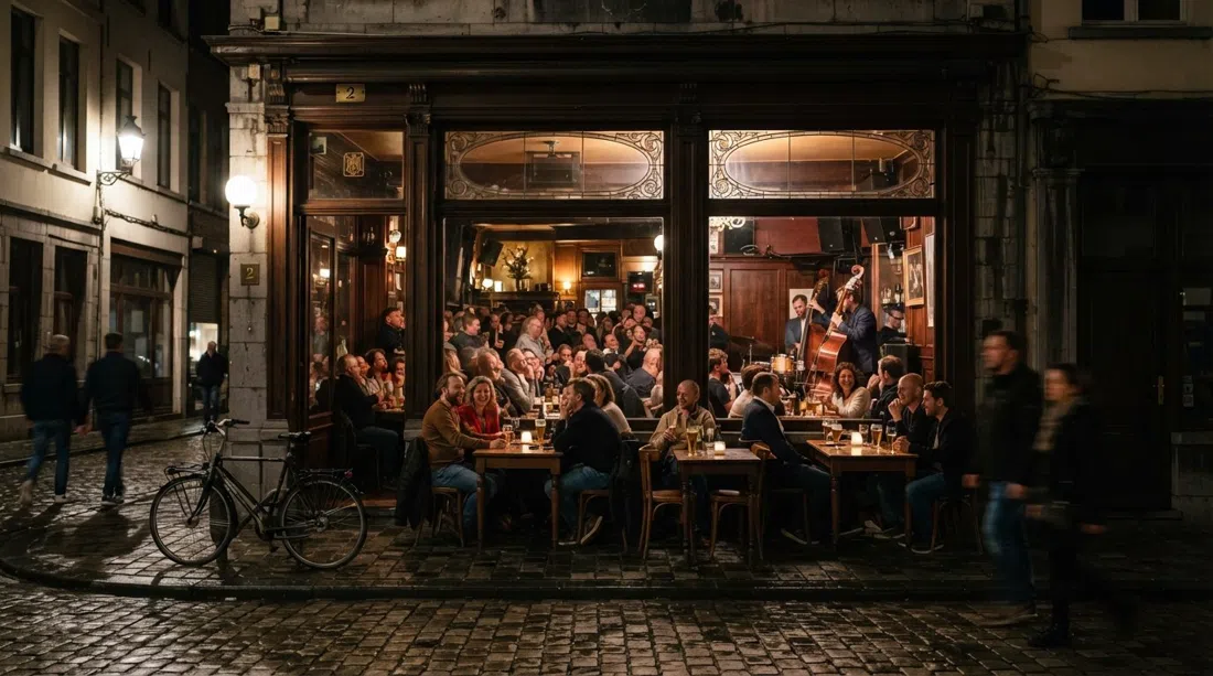 Café Hopper en Leopold de Waelstraat 2 de noche, ventanas cálidas, vasos de cerveza en las mesas y un pequeño público de jazz dentro